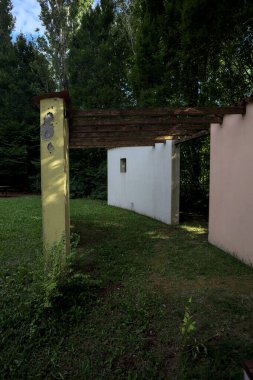 Parktaki bir grup ağacın arkasındaki ev cephesi şeklinde sanatsal kurulum