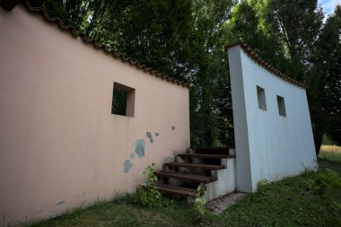 Parktaki bir grup ağacın arkasındaki ev cephesi şeklinde sanatsal kurulum