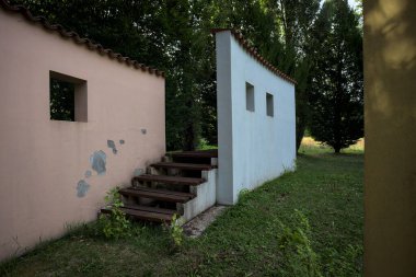 Parktaki bir grup ağacın arkasındaki ev cephesi şeklinde sanatsal kurulum