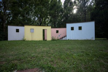 Parktaki bir grup ağacın arkasındaki ev cephesi şeklinde sanatsal kurulum