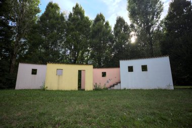 Parktaki bir grup ağacın arkasındaki ev cephesi şeklinde sanatsal kurulum