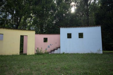 Parktaki bir grup ağacın arkasındaki ev cephesi şeklinde sanatsal kurulum