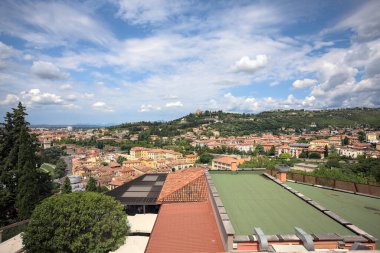 Güneşli bir günde bir ormanla kaplı bir tepeye tırmanan bir kasabanın binaları
