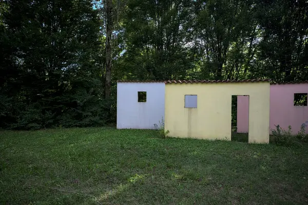 Parktaki bir grup ağacın arkasındaki ev cephesi şeklinde sanatsal kurulum