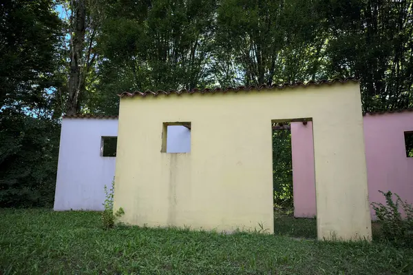 Parktaki bir grup ağacın arkasındaki ev cephesi şeklinde sanatsal kurulum