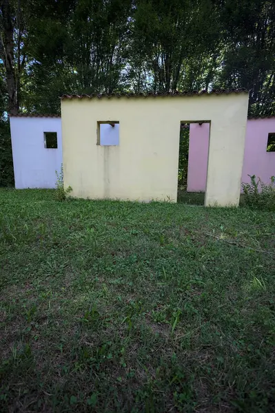 Parktaki bir grup ağacın arkasındaki ev cephesi şeklinde sanatsal kurulum