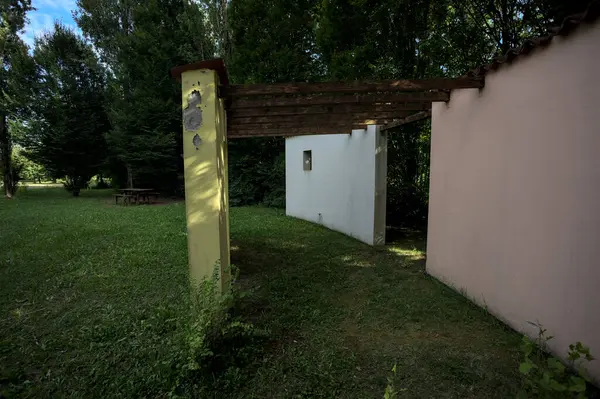 Parktaki bir grup ağacın arkasındaki ev cephesi şeklinde sanatsal kurulum