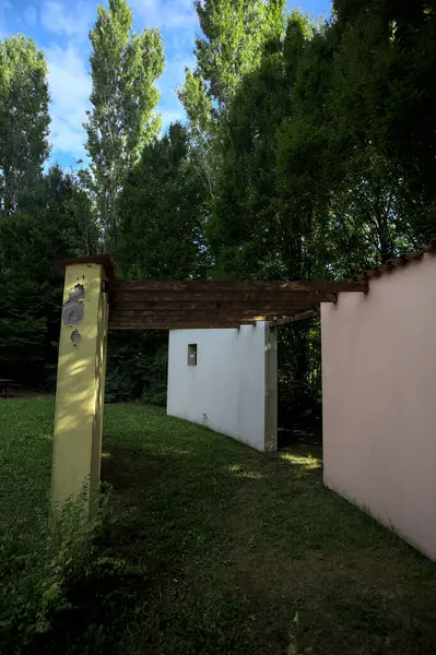 Parktaki bir grup ağacın arkasındaki ev cephesi şeklinde sanatsal kurulum