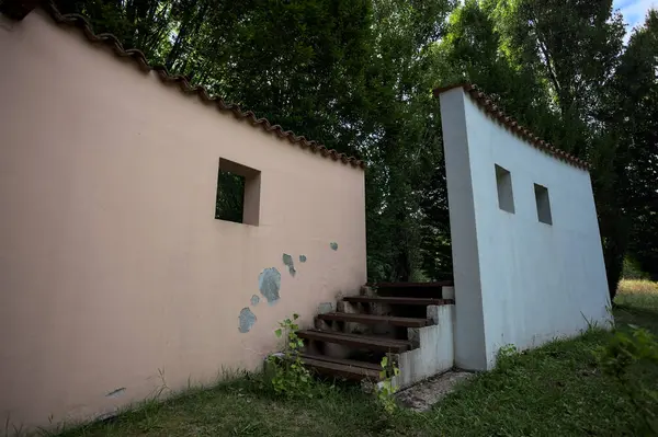 Parktaki bir grup ağacın arkasındaki ev cephesi şeklinde sanatsal kurulum