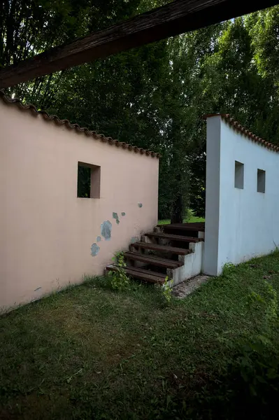 Parktaki bir grup ağacın arkasındaki ev cephesi şeklinde sanatsal kurulum