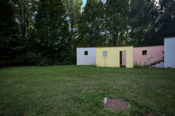 Parktaki bir grup ağacın arkasındaki ev cephesi şeklinde sanatsal kurulum