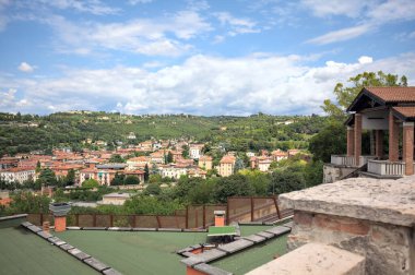 Güneşli bir günde bir ormanla kaplı bir tepeye tırmanan bir kasabanın binaları