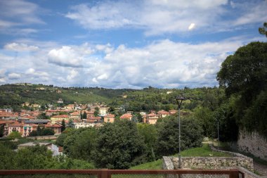 Güneşli bir günde bir ormanla kaplı bir tepeye tırmanan bir kasabanın binaları