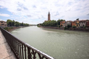 Verona, İtalya - 30 Temmuz 2025 - Santa Anastasia Kilisesi ve yanındaki binalar Adige nehri kıyısında karşı kıyıdaki bir demiryolunun arkasında görüldü.