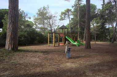 Bulutlu bir günde, deniz çamı koruluğunda boş bir oyun alanı