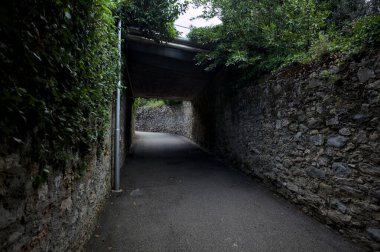 Bulutlu bir günde, İtalya 'nın bir köyünde ağaçlarla çevrili taştan duvarlarla çevrili taştan bir geçit.