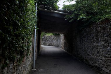 Bulutlu bir günde, İtalya 'nın bir köyünde ağaçlarla çevrili taştan duvarlarla çevrili taştan bir geçit.