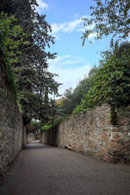 Bulutlu bir günde, İtalya 'nın bir köyünde ağaçlarla çevrili taştan duvarlarla çevrili taştan bir geçit.