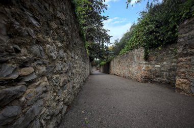 Bulutlu bir günde, İtalya 'nın bir köyünde ağaçlarla çevrili taştan duvarlarla çevrili taştan bir geçit.