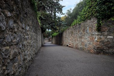 Bulutlu bir günde, İtalya 'nın bir köyünde ağaçlarla çevrili taştan duvarlarla çevrili taştan bir geçit.