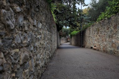 Bulutlu bir günde, İtalya 'nın bir köyünde ağaçlarla çevrili taştan duvarlarla çevrili taştan bir geçit.