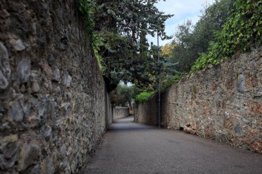 Bulutlu bir günde, İtalya 'nın bir köyünde ağaçlarla çevrili taştan duvarlarla çevrili taştan bir geçit.