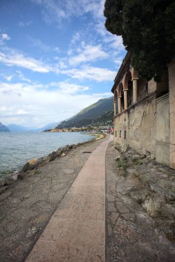 Bulutlu bir günde göl kıyısında tarihi bir binayla çevrili taş ve mermer patika izleri.