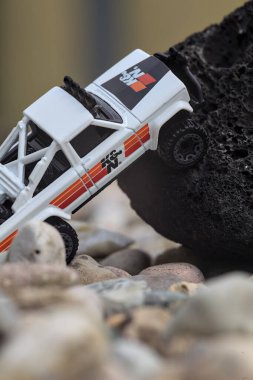 Mantova, İtalya - 27. AĞUSTOS 2025 - 1973 model beyaz bir Jeep J10 'un siyah bir kayanın üzerindeki Hot Wheels kopyası.