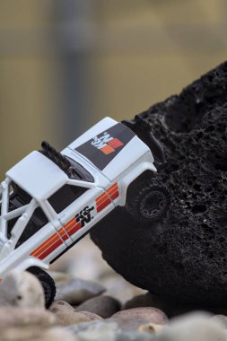 Mantova, İtalya - 27. AĞUSTOS 2025 - 1973 model beyaz bir Jeep J10 'un siyah bir kayanın üzerindeki Hot Wheels kopyası.