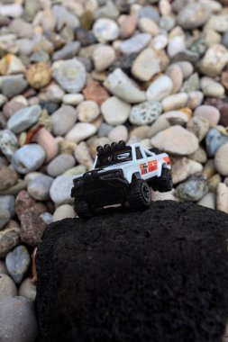 Mantova, İtalya - 27. AĞUSTOS 2025 - 1973 model beyaz bir Jeep J10 'un siyah bir kayanın üzerindeki Hot Wheels kopyası.