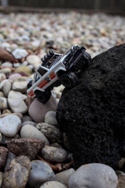 Mantova, İtalya - 27. AĞUSTOS 2025 - 1973 model beyaz bir Jeep J10 'un siyah bir kayanın üzerindeki Hot Wheels kopyası.