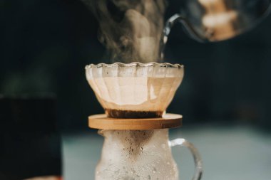 Kahve dükkanında filtreli kahve yapıyorum. Bir damla sıcak espresso hazırlamak, sıcak suyla kahvenin üzerine dökmek ve evde filtre kağıdı dökmek..