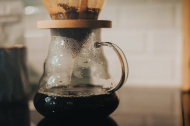 Kahve dükkanında filtreli kahve yapıyorum. Bir damla sıcak espresso hazırlamak, sıcak suyla kahvenin üzerine dökmek ve evde filtre kağıdı dökmek..