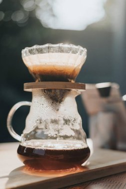 Kahve dükkanında filtreli kahve yapıyorum. Bir damla sıcak espresso hazırlamak, sıcak suyla kahvenin üzerine dökmek ve evde filtre kağıdı dökmek..