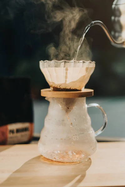 Making filtered drip coffee in coffee shop. Close up of brewing a drip hot espresso, pour over coffee with hot water and filter paper at home.