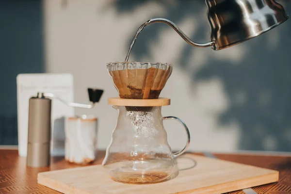 Making filtered drip coffee in coffee shop. Close up of brewing a drip hot espresso, pour over coffee with hot water and filter paper at home.