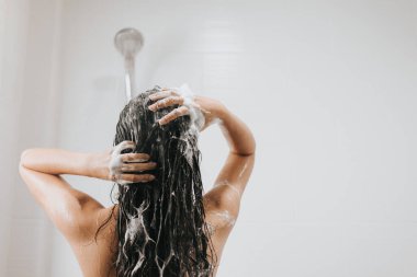 Kadın saçını şampuanla yıkıyor ve banyoda duş alıyor, Asyalı kadın vücudu ve köpükle saç bakımı yapıyor. Spa ve Sağlık Hizmetleri.