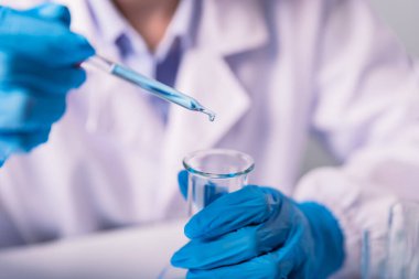 Kimyager, bilim adamı, kimyasal sıvıyı test tüpüne, bilim araştırmaları ve geliştirme konseptine yerleştirip bırakıyor.