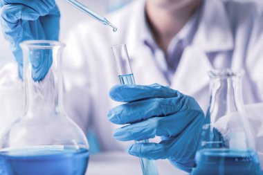 Kimyager, bilim adamı, kimyasal sıvıyı test tüpüne, bilim araştırmaları ve geliştirme konseptine yerleştirip bırakıyor.