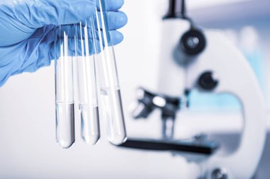 Kimyager, bilim adamı, laboratuvar arka planı, bilimsel araştırma ve geliştirme konseptinde mikroskop ile test tüpü tutuyor.