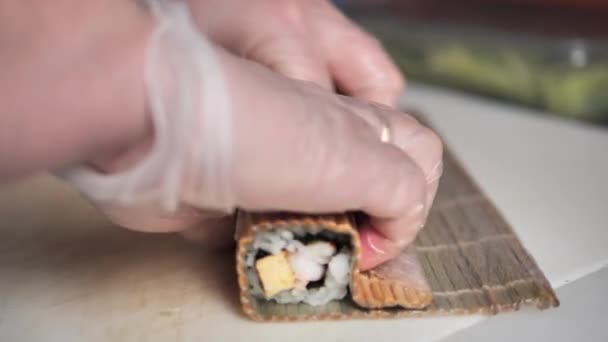 日本料理のマスターは タケマットの上に熟練した寿司ロールを紡いでくれる専門知識を紹介します これらの美味しいロールを作る複雑なプロセスは魅了されています — ストック動画