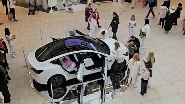 ラトビア April 2024 テスラの電気自動車は 賞賛者に囲まれたスポットライトを盗みます テスラの車の各詳細は 好奇心旺盛な買い物客テスラによって検査され 最先端の技術エディトリアルを紹介します — ストック動画