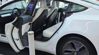 Riga, Letonya -20 Nisan 2024: Tesla elektrikli otomobili ilgi odağı: İzleyiciler Tesla 'nın çevre dostu teknolojisini tartışmak için duraklıyor. Tesla arabası, sürücünün geleceğini yansıtıyor