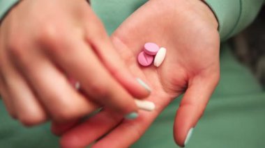Bu videoda yeşil tırnaklı kadınların elleri ve giysi parmakları avuçlarında haplar olarak kabul ediliyor. Hareket, haplarla etkileşimi vurguluyor Sağlık Konsepti