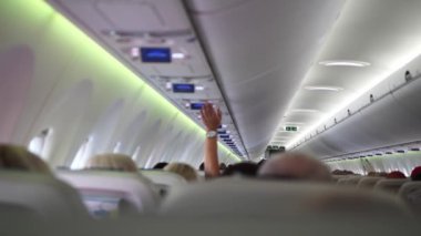 Oturan yolcularla dolu yolcu kabini. Bazıları, yolcu kabinindeki dinamik atmosferi gösteren yolcu kabinlerini ayarlamak için ellerini kaldırıyor..