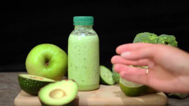 Şişe içinde sağlıklı yeşil smoothie, masadaki tahtadan meyve püresi toplamak. Avokado, limonlu brokoli, salatalık sağlıklı ve besinle ilgili mükemmel meyve suyu seçimi.