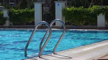 Suya giden metal merdiveni olan mavi yüzme havuzu. Yaz ve eğlence için mükemmel. Yüzme havuzunun sakin sahnesini çek, rahatlamaya ve yüzme havuzunun temiz suyuna davetiye çıkar. 