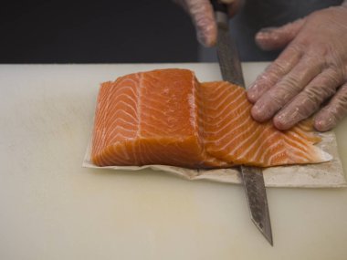 Somon filetoları bir Japon mutfak ustası tarafından ustaca dilimlenir. Her kesik somon balığının canlı rengini ve narin dokusunu ortaya çıkarıyor. Her parça kusursuzca oyuluyor..