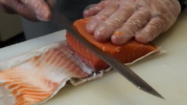 Taze somon, yetenekli bir şef tarafından ince ince dilimlenir. Her kesik somonun canlı rengini vurguluyor. Tazeliğini ve şefin detaylara olan ilgisini yansıtıyor..