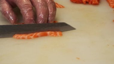 Japon bir mutfak ustası özel bir bıçakla taze somonu parçalara ayırıyor. Kesikleri somon balığının hassas dokusunu ortaya çıkararak mükemmel hazırlanmış somon porsiyonlarını oluşturuyor..